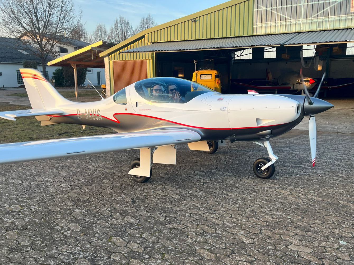 Ultraleicht Flugzeug vor einem Hangar im Freien geparkt.