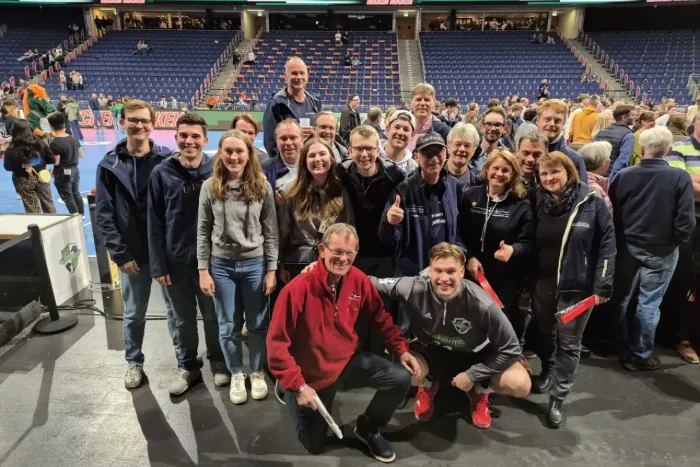 Gruppe von Menschen im Stadion lächelnd in die Kamera.